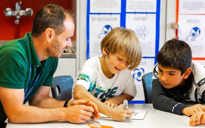 An ISL's teacher with two young students drawing