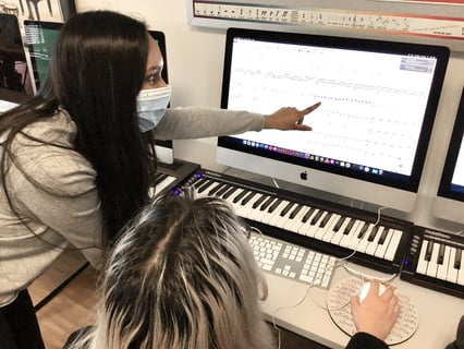 Two ISL students making music using a piano and a computer