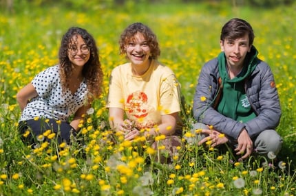 Three smiling ISL students in the school's community garden